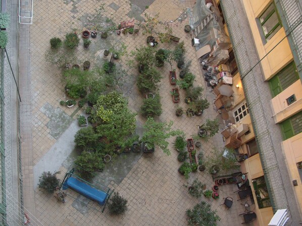 An aerial view of a courtyard with potted plants, a blue bench, and a small fountain.