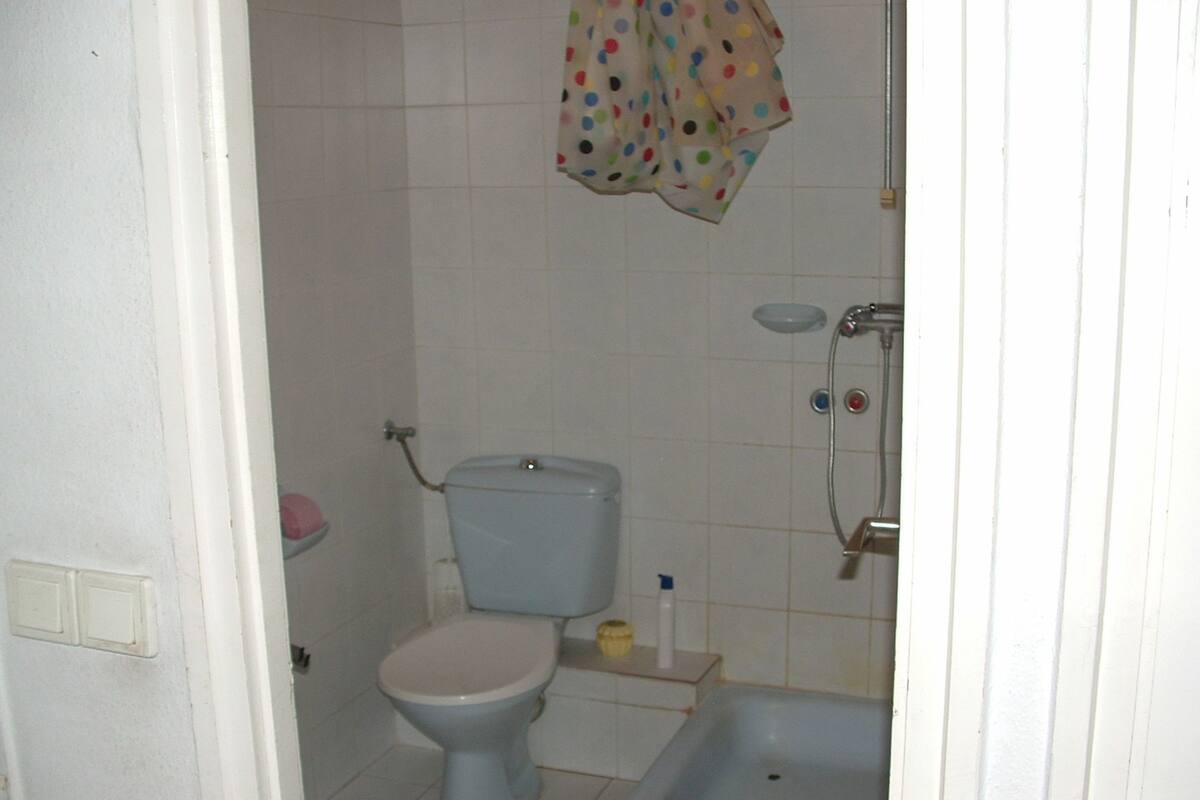 Un baño pequeño con inodoro, lavamanos y ducha.