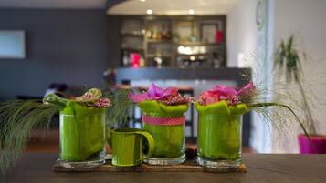 Three green glass mugs with pink flowers and greenery on a wooden table.