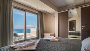 Habitación de hotel con una cama grande, un baño y vistas al mar.
