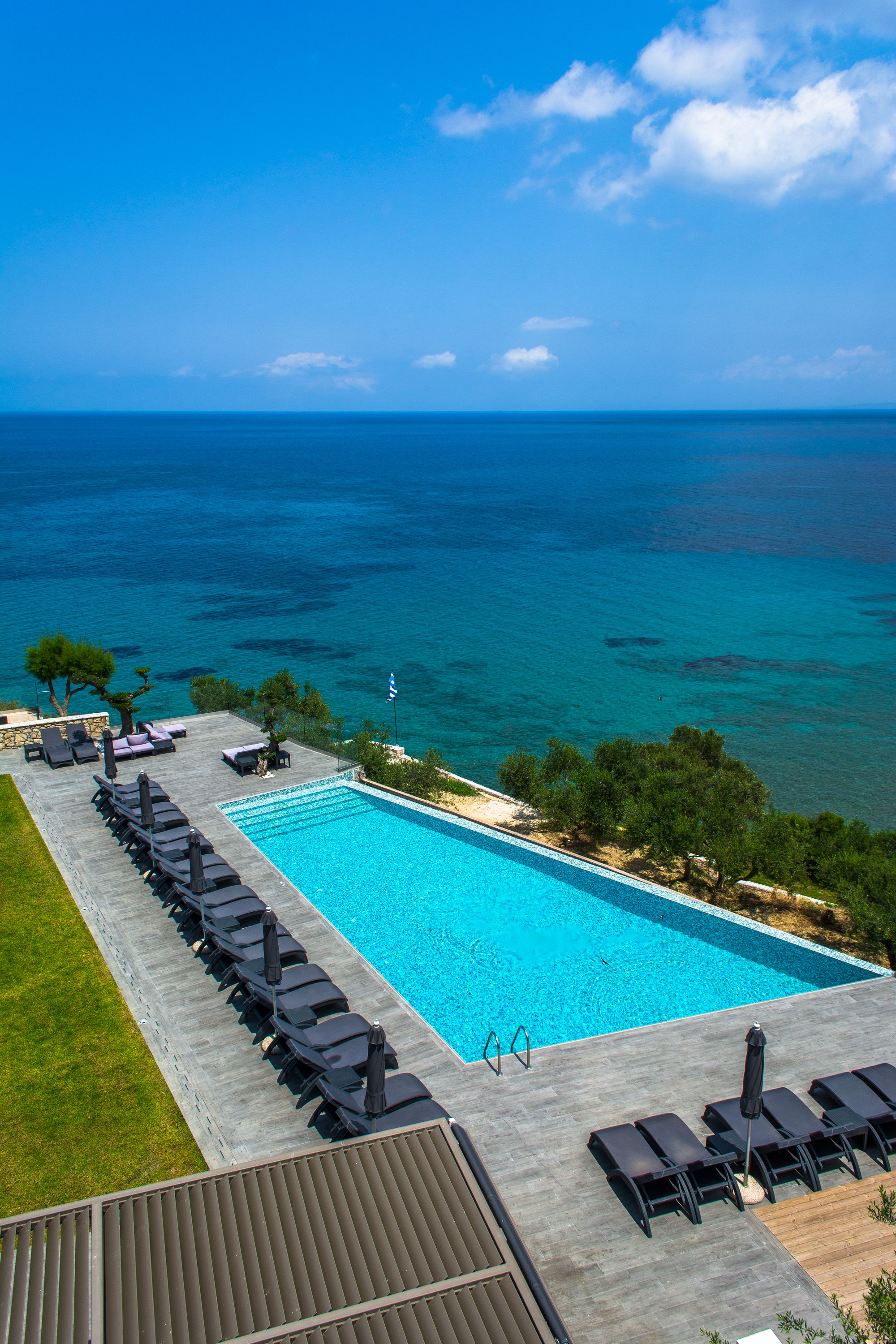 Una piscina con sillas de descanso y vistas al mar.