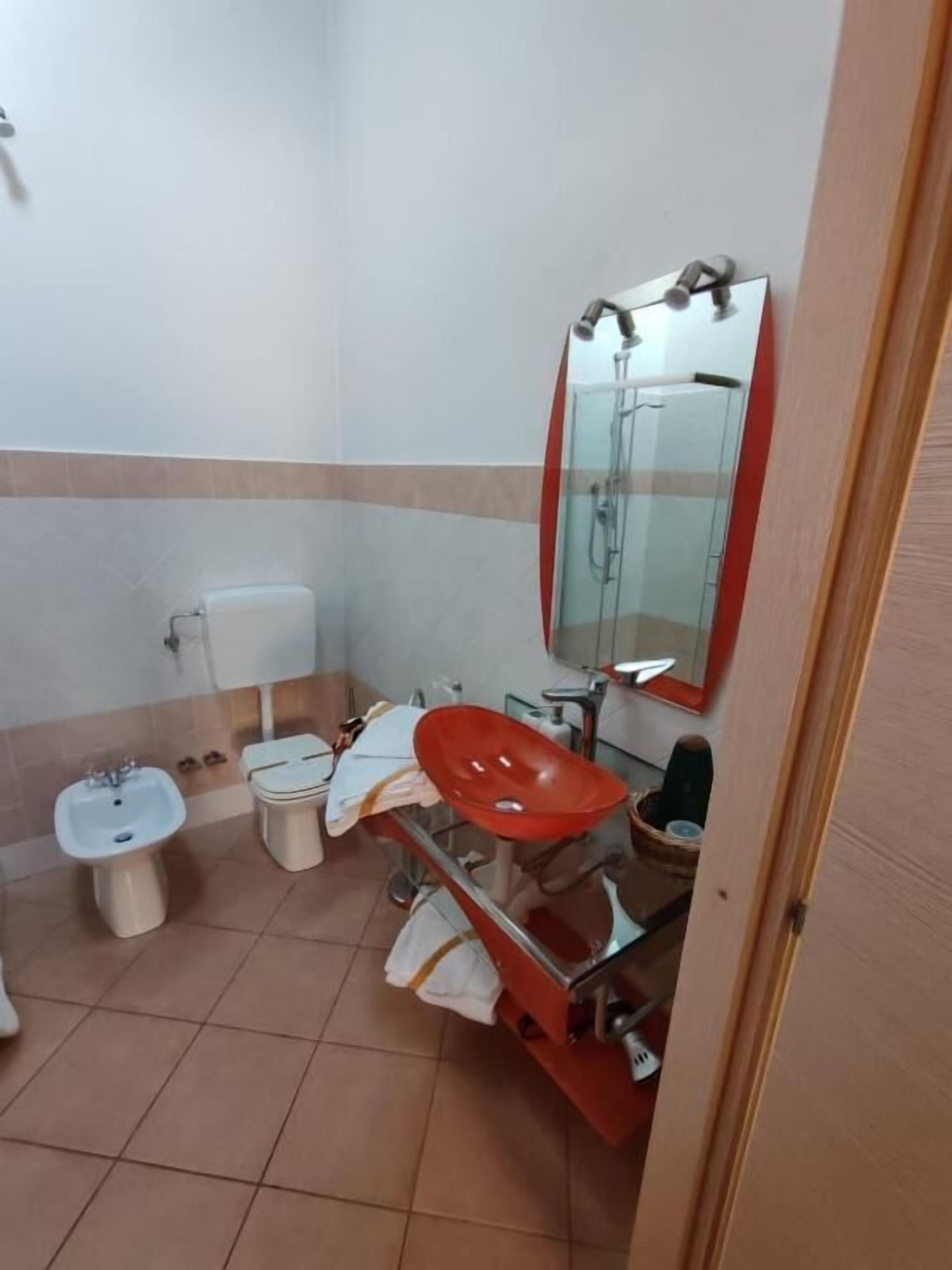 Un baño con inodoro, bidé y lavamanos con espejo.