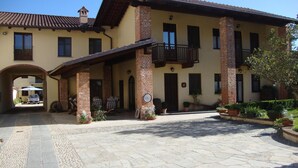 A two-story building with a tiled roof, a balcony, and a paved courtyard. - Al Calar della Sera (Sommariva del Bosco)