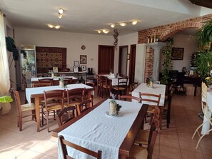 A restaurant with multiple tables and chairs, a brick wall, and hanging lights. - Al Calar della Sera (Sommariva del Bosco)