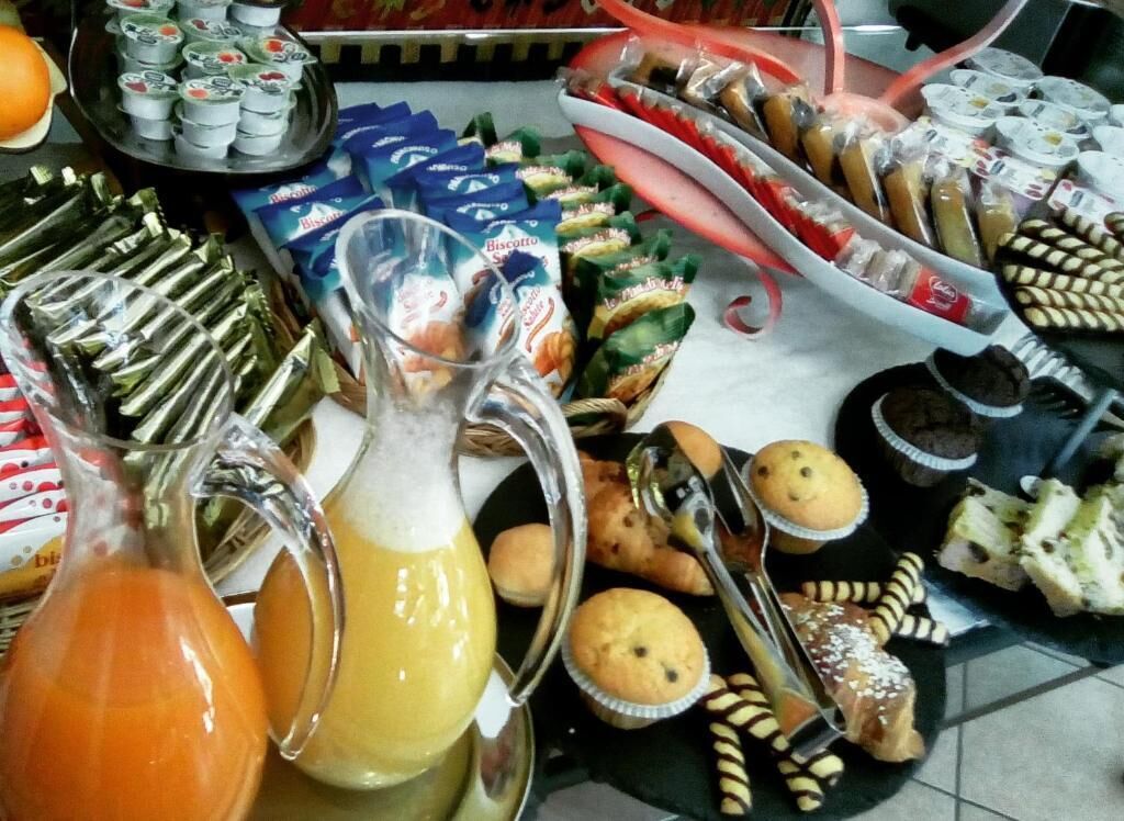 A buffet table with various food items including pastries, muffins, and beverages.