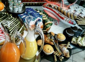 Une table de buffet proposant divers plats, notamment des pâtisseries, des muffins et des boissons.