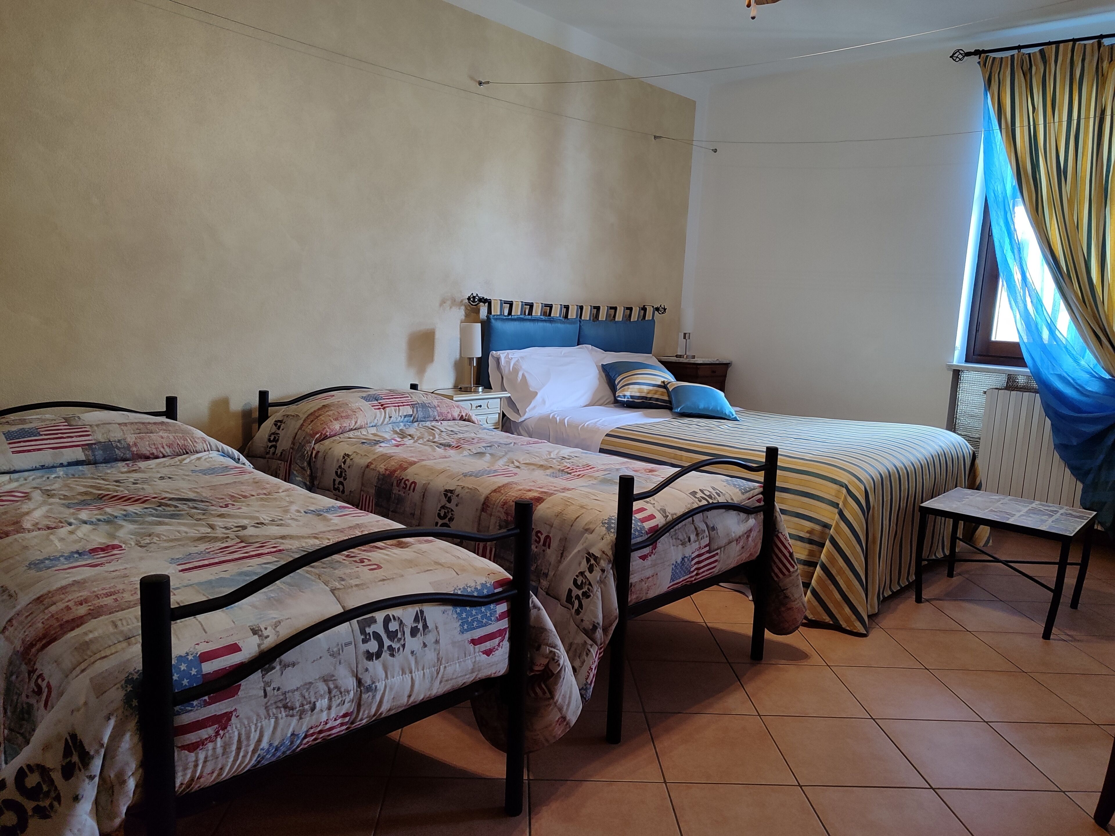 Una habitación con dos camas, una mesita y una ventana con cortinas.