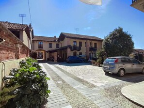 A residential building with a paved driveway, a parked car, and a garden area. - Al Calar della Sera (Sommariva del Bosco)