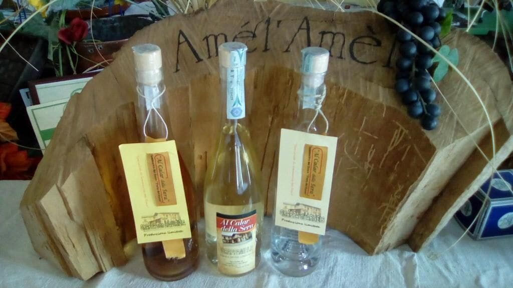 Three bottles of wine with labels, placed on a wooden surface with a carved design.