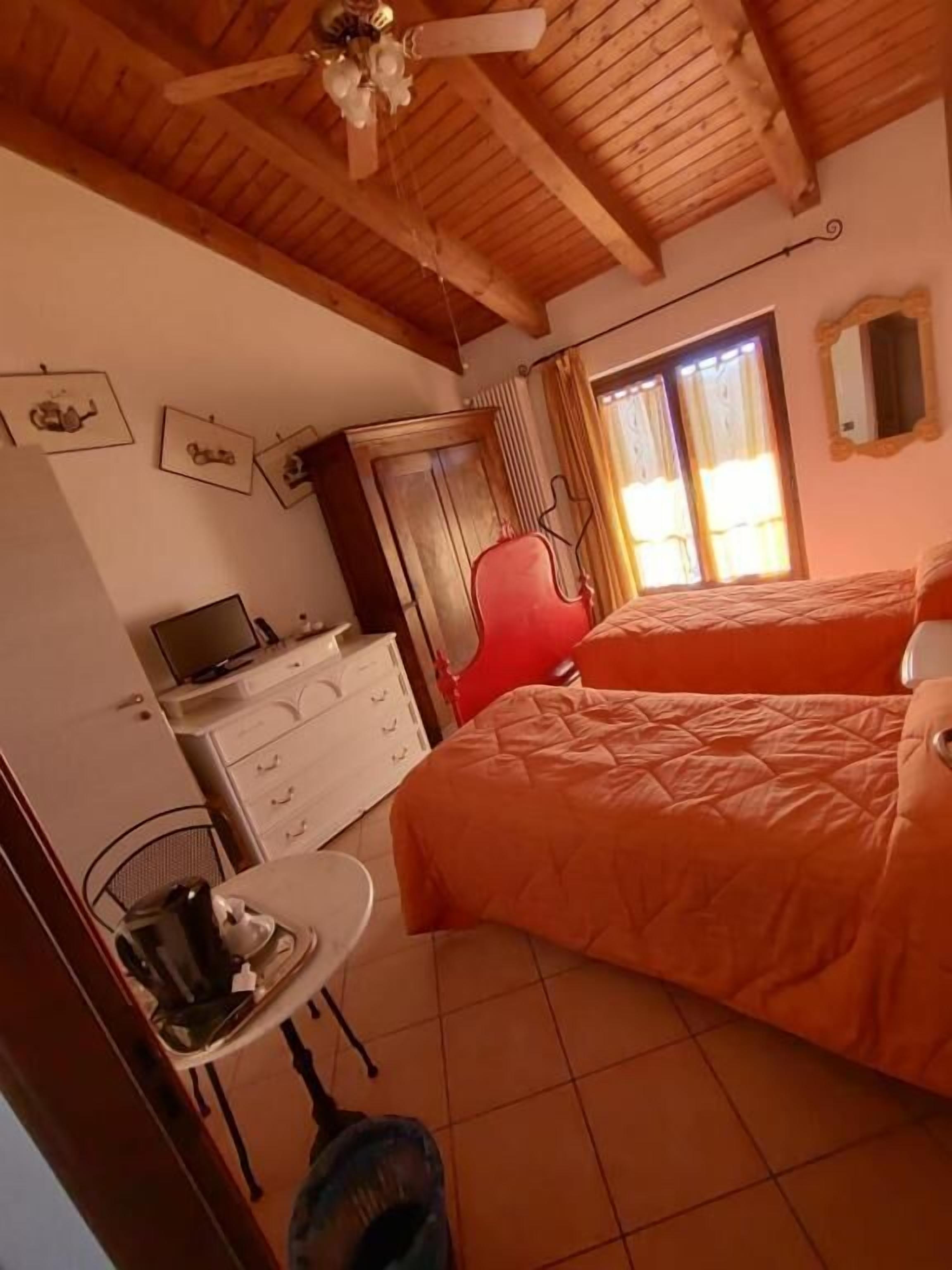 A room with a bed, a desk, a chair, and a ceiling fan.