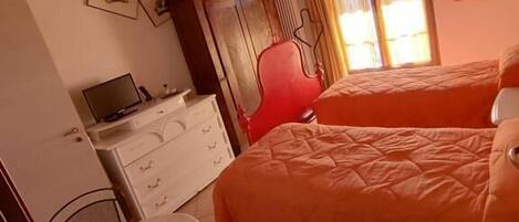 A room with a bed, a desk, a chair, and a ceiling fan.