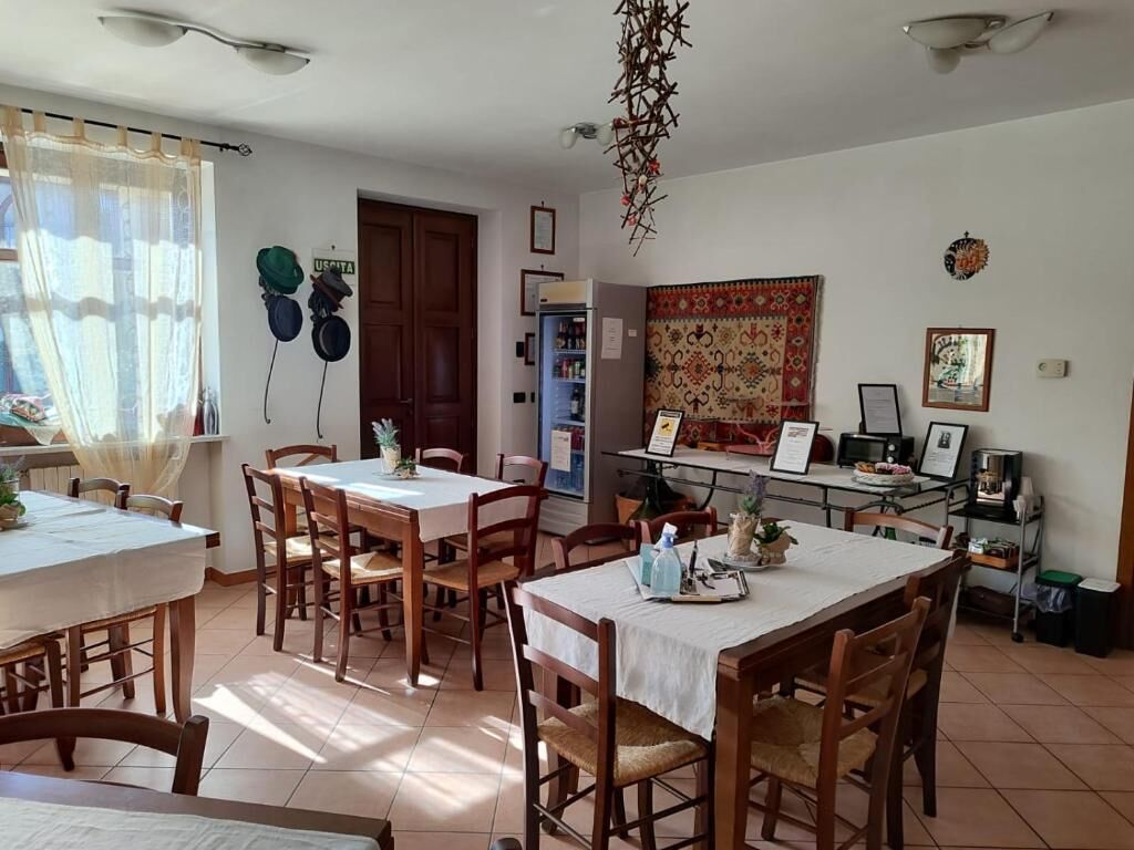 Un espace repas comprenant plusieurs tables et chaises, un réfrigérateur et une décoration murale à motifs.