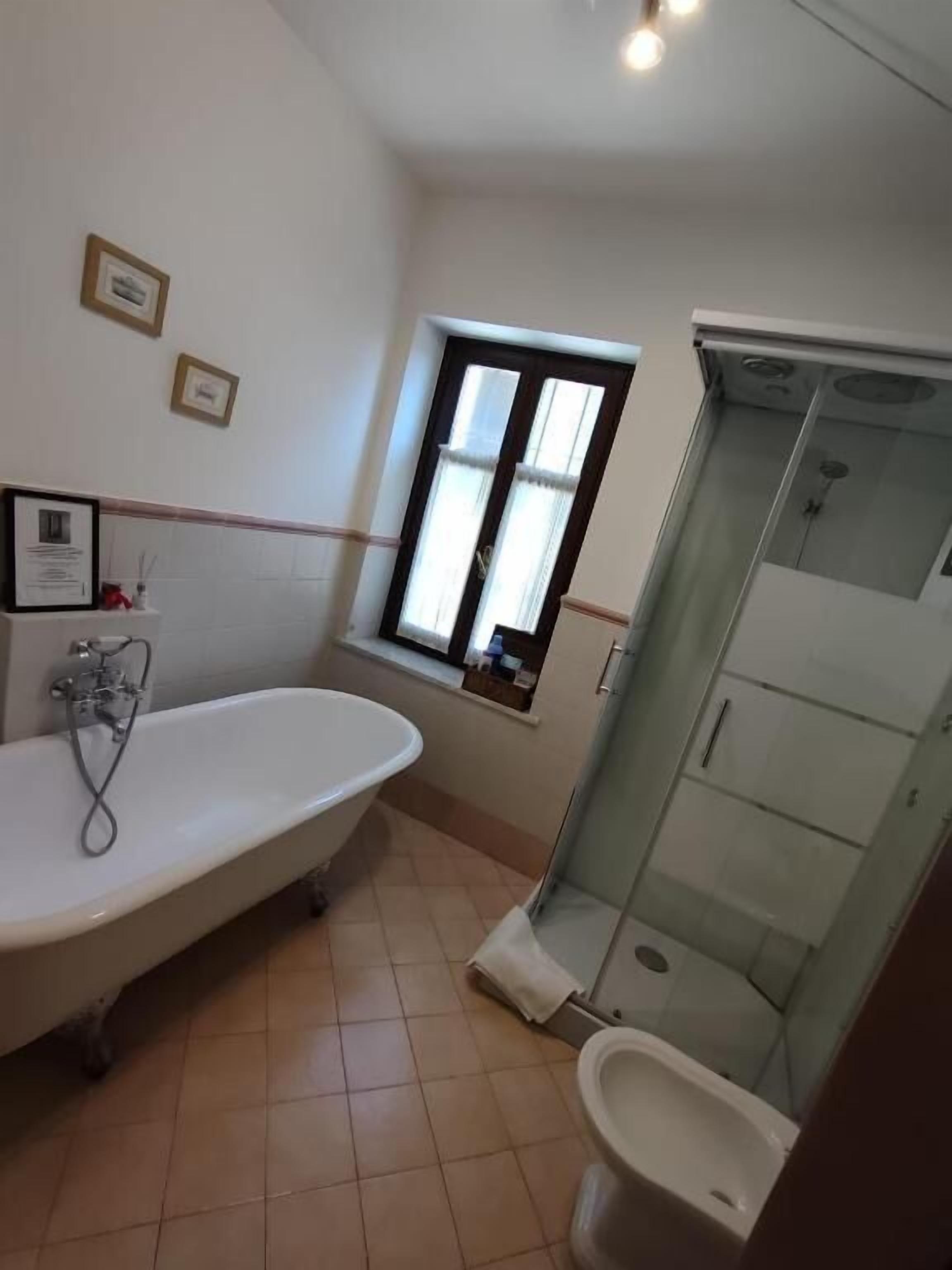 A bathroom with a bathtub, toilet, and glass-enclosed shower.
