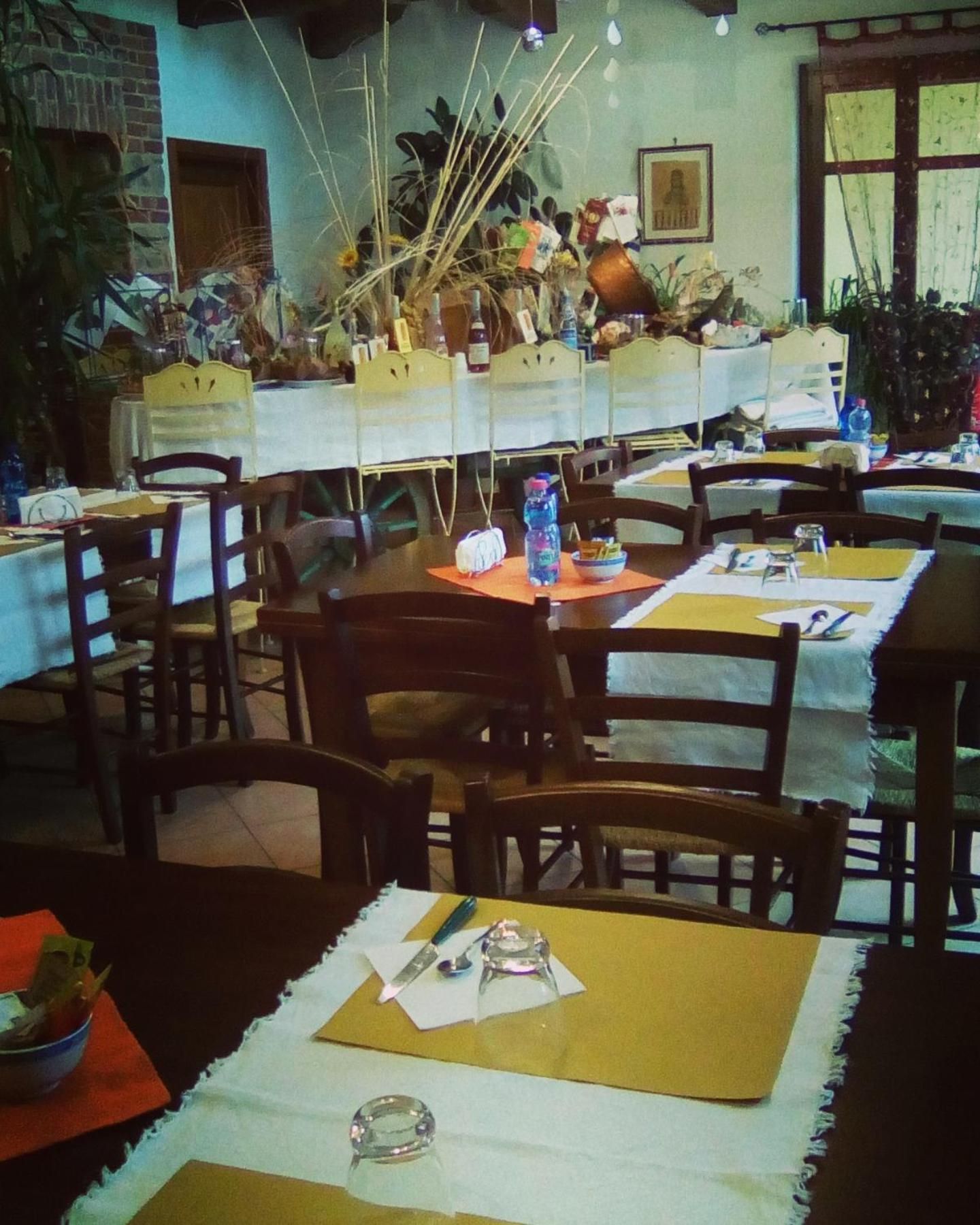 A dining area with multiple tables and chairs, some with placemats and cutlery.