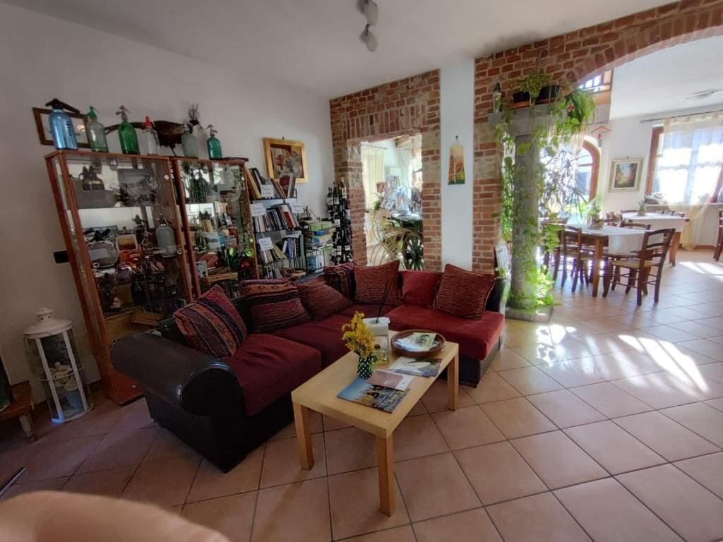 Ein geräumiges Wohnzimmer mit Ziegelwand, einer Sofagarnitur, einem Couchtisch und einem Essbereich mit Stühlen.