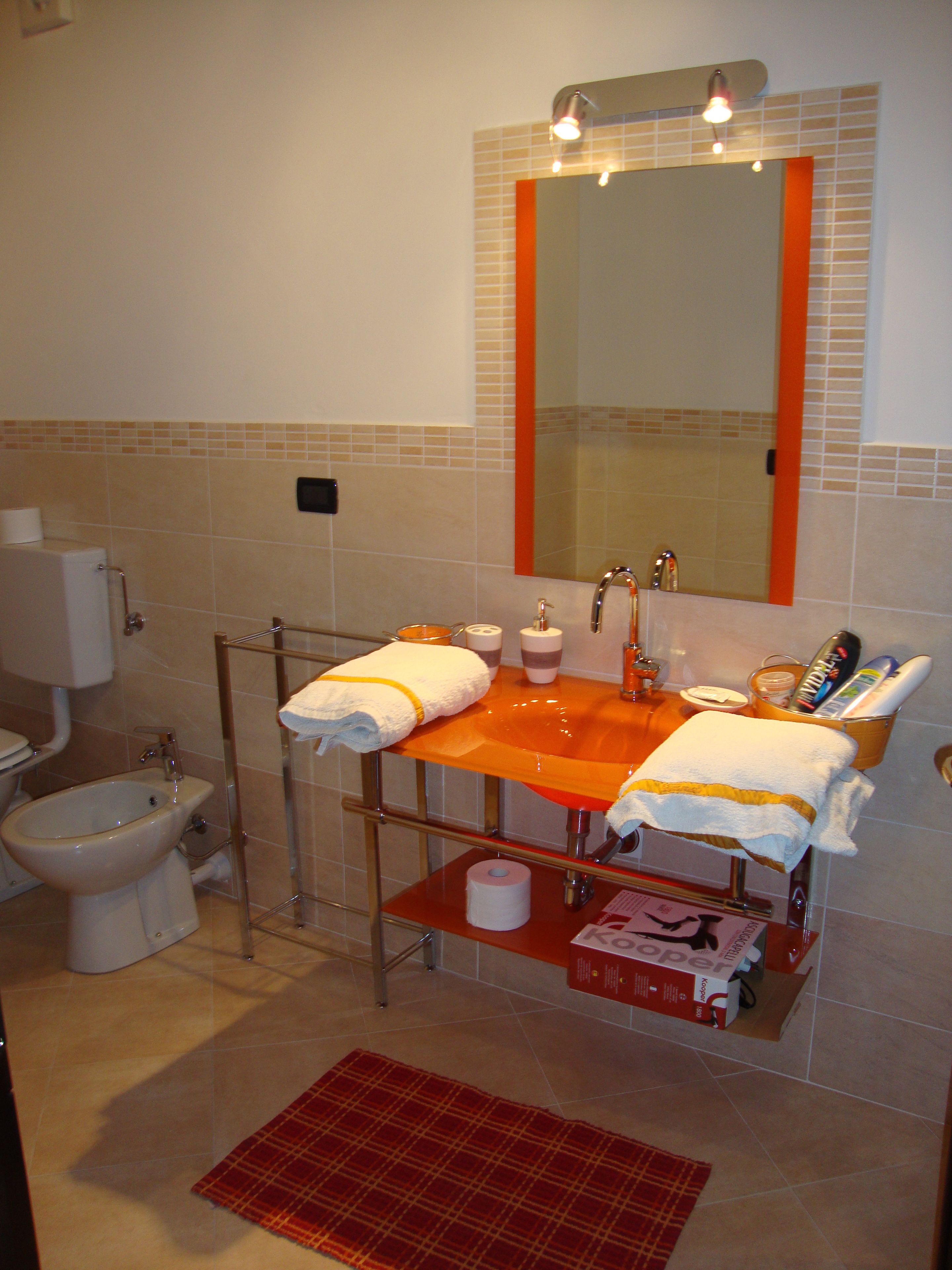 A bathroom with a bidet, a sink with a mirror above it, and a towel rack with towels.