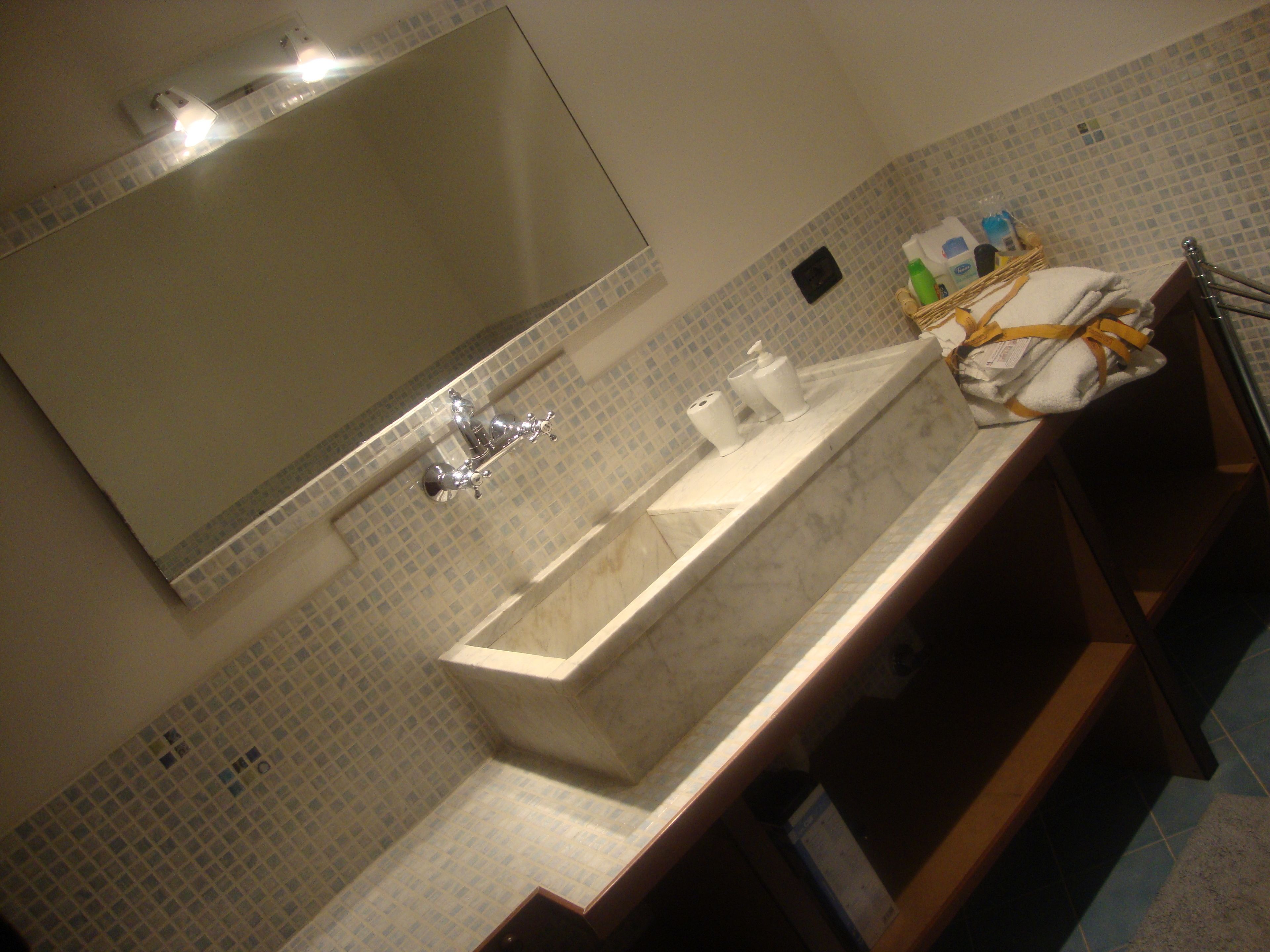A bathroom with a large mirror, a sink, and a towel rack.