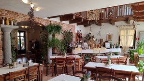 A cozy restaurant with brick walls, wooden beams, and multiple tables and chairs. - Al Calar della Sera (Sommariva del Bosco)