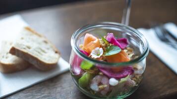 A clear glass bowl containing a salad with various ingredients, accompanied by slices of bread on a white napkin.