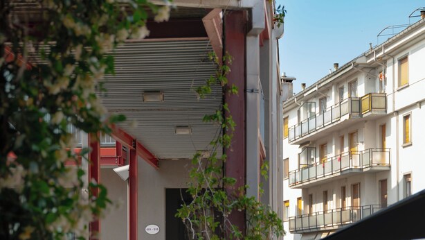 An outdoor seating area with a table and chairs, a covered walkway, and a building with balconies in the background. - Residenze Romeo e Giulietta  (Parma)