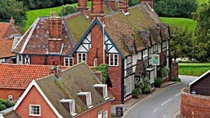 Un bâtiment de style Tudor traditionnel, doté d’un toit à forte pente, de nombreuses cheminées et d’une enseigne indiquant qu’il s’agit d’un pub.