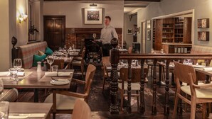 Un restaurant doté de meubles en bois, d’une cheminée et d’un coin bar.