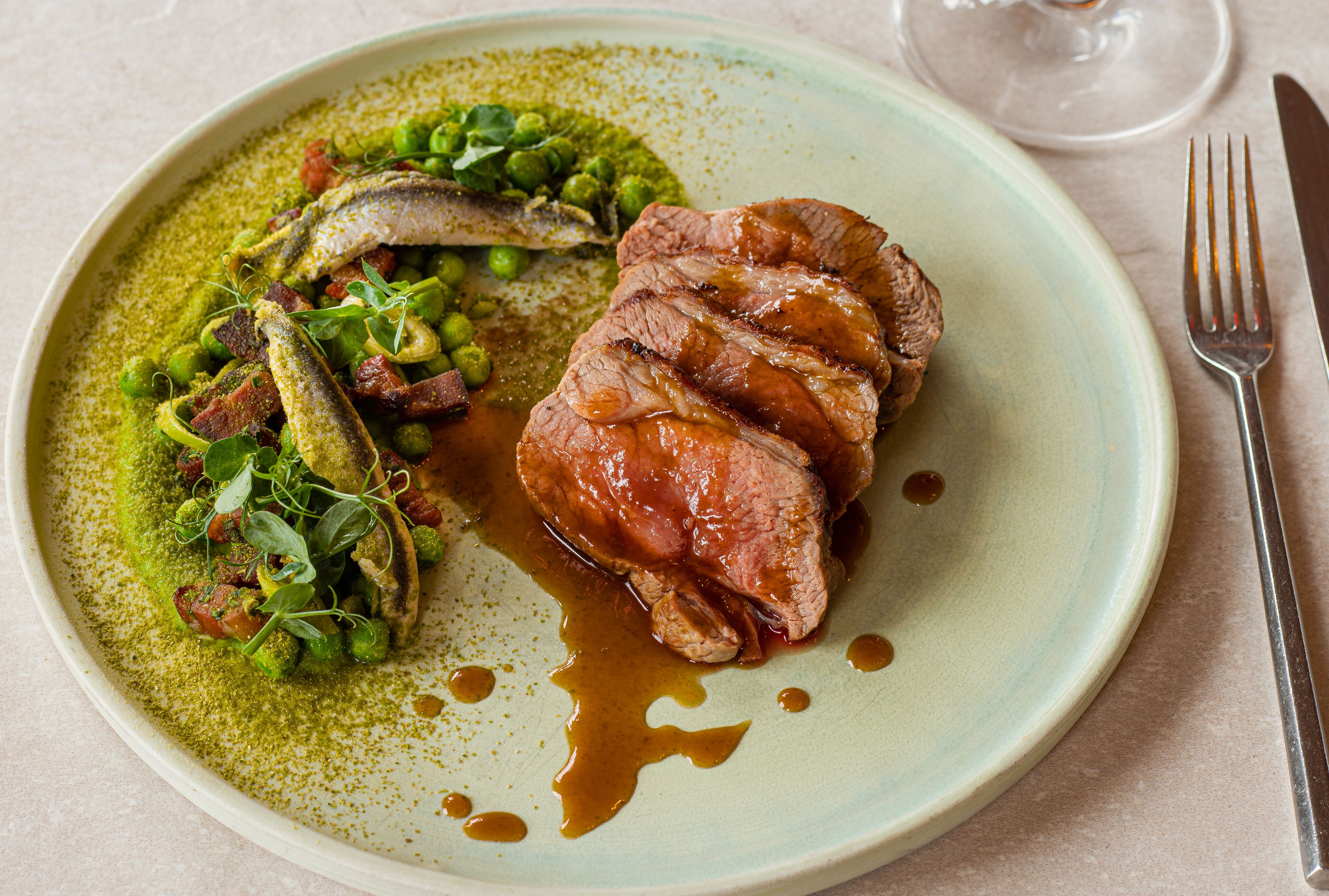 Une assiette de nourriture composée de viande, de petits pois et de sauce.