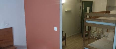 Una habitación con literas, una silla y un escritorio con otra silla.