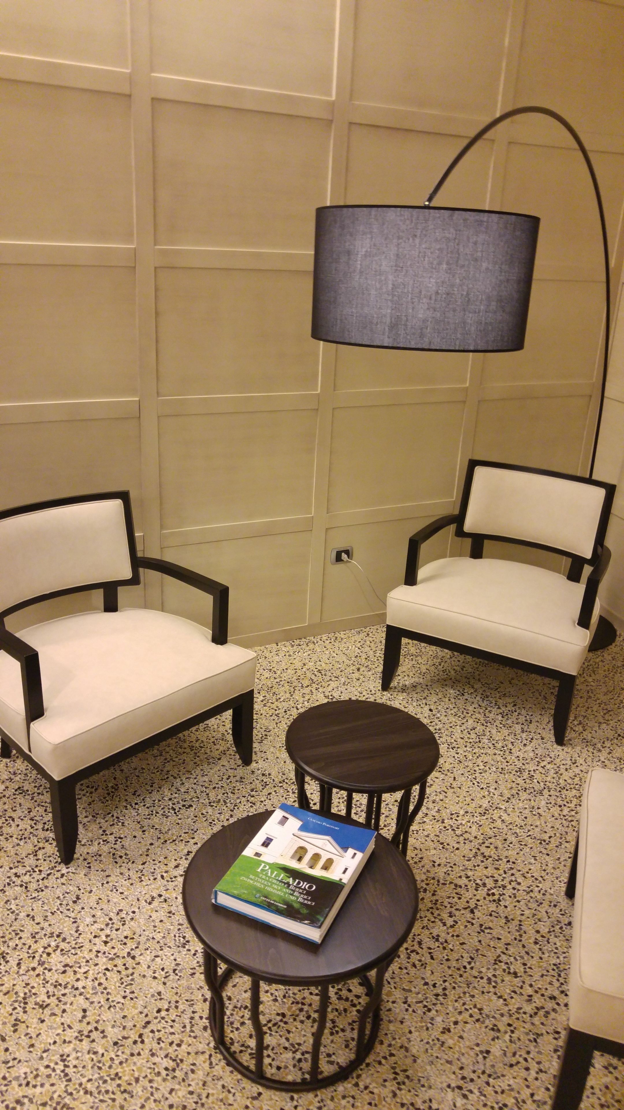 A room with two armchairs, a small round table with a book, and a floor lamp.