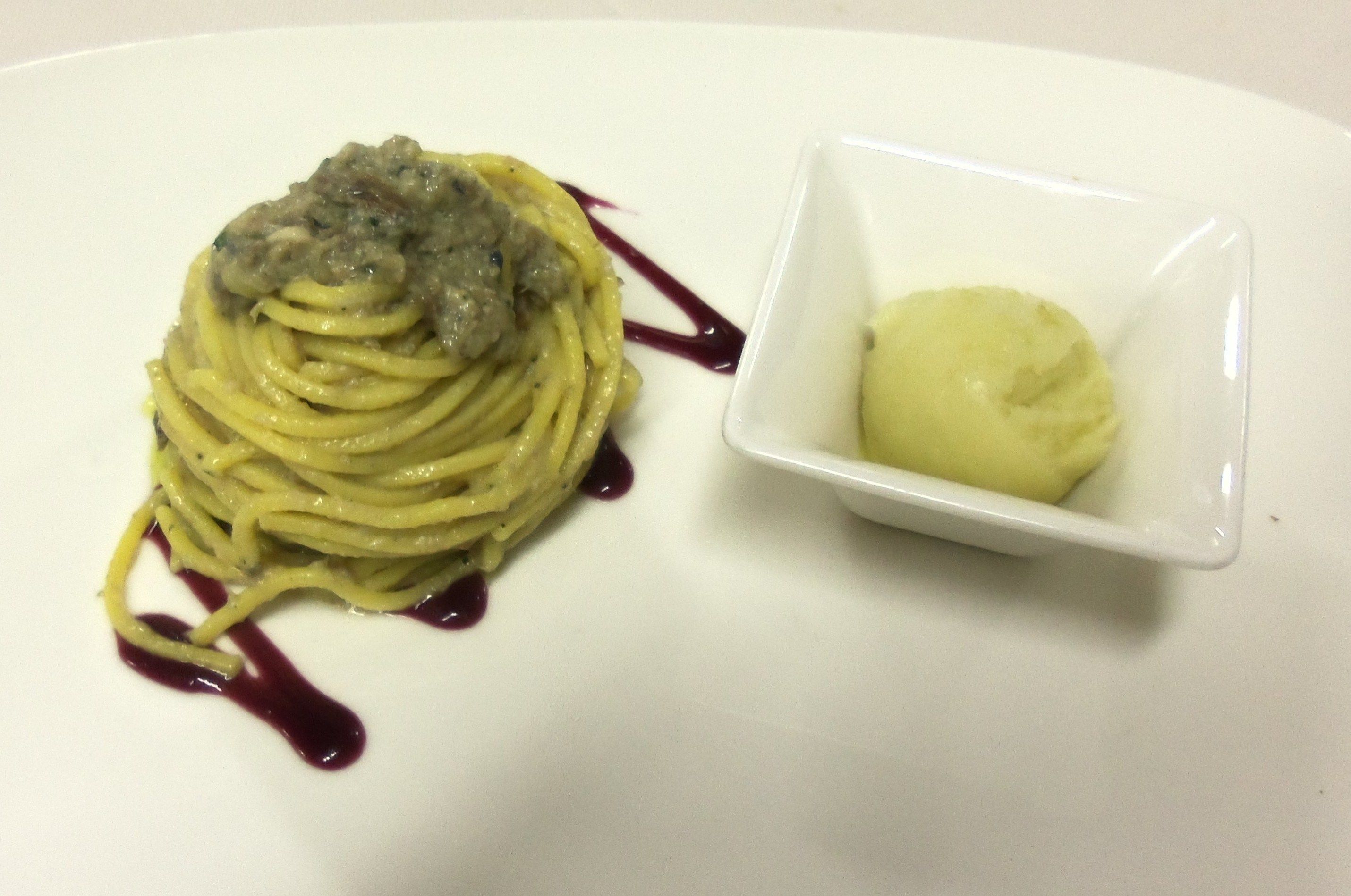 A plate of spaghetti with a creamy topping and a small bowl of a yellow dessert.