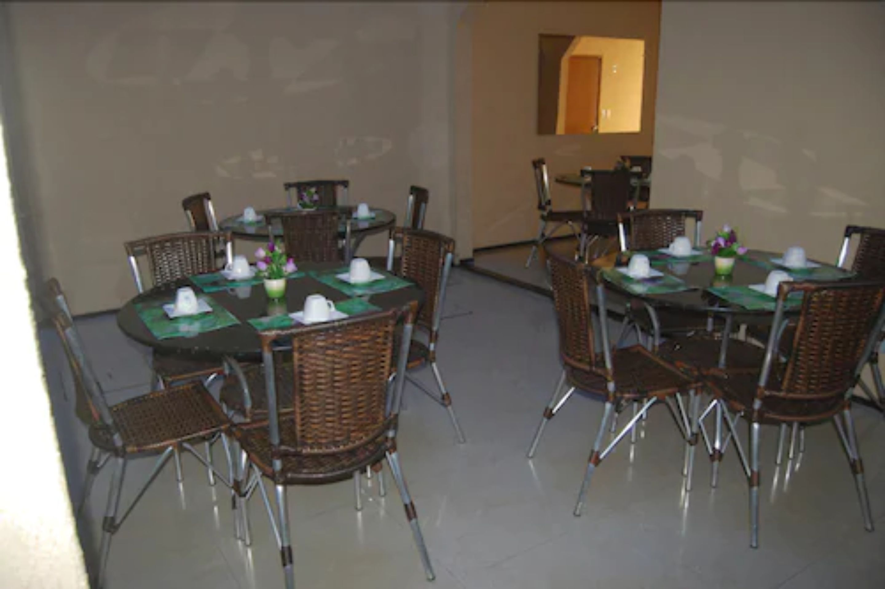 A conference room with round tables and wicker chairs, equipped with nameplates and place settings.
