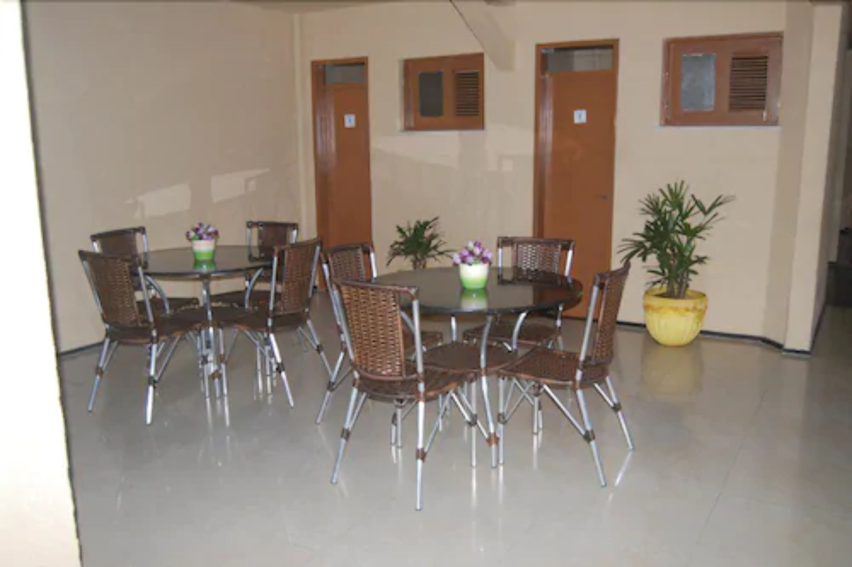 Uma sala de conferências com uma mesa redonda, oito cadeiras de vime e uma planta em vaso.