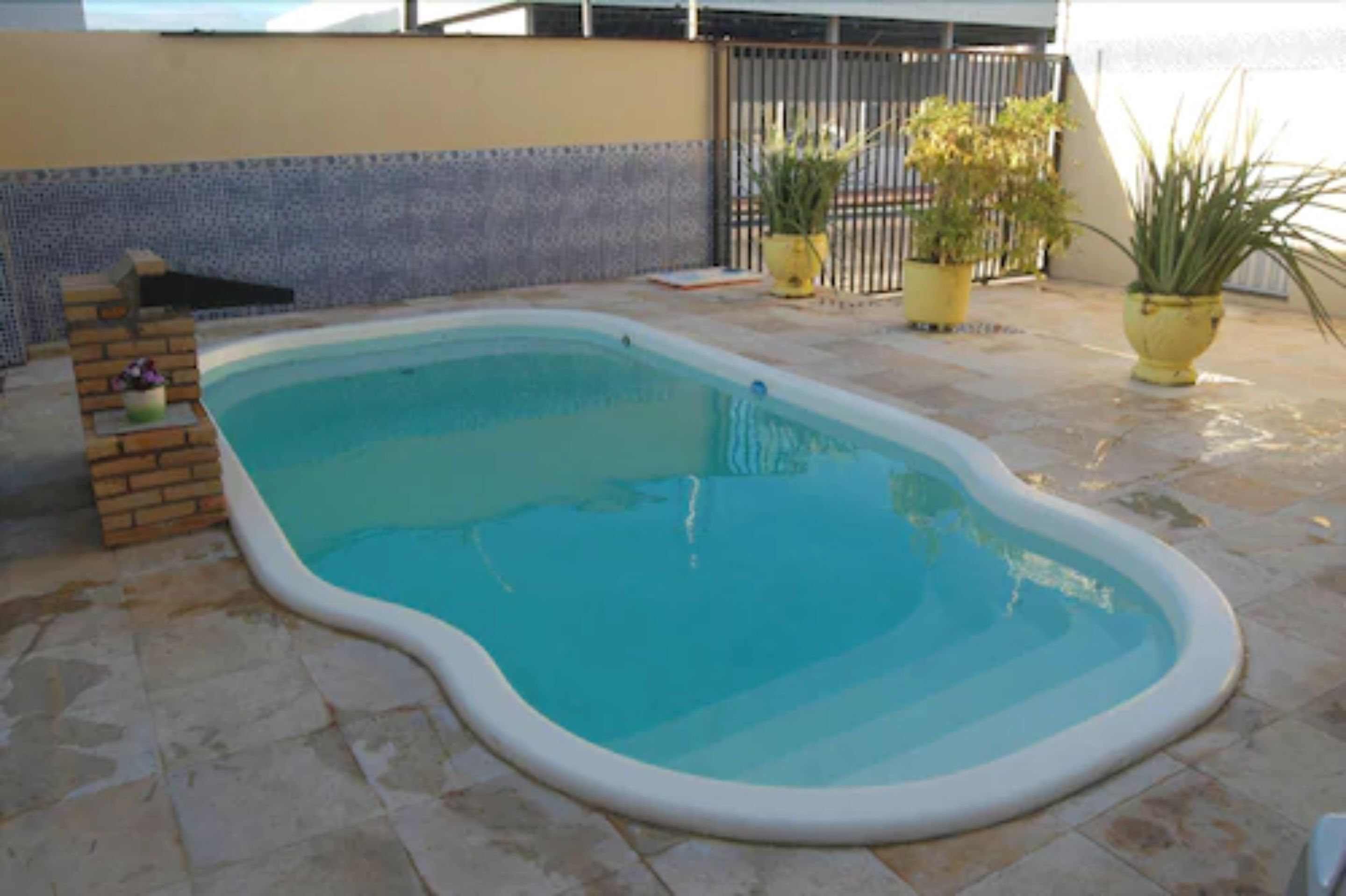 Una piscina con struttura in mattoni e piante in vaso tutt'intorno.