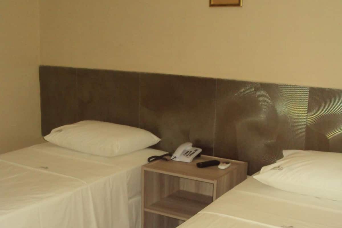 A hotel room with two single beds, a bedside telephone, and a small wooden nightstand.