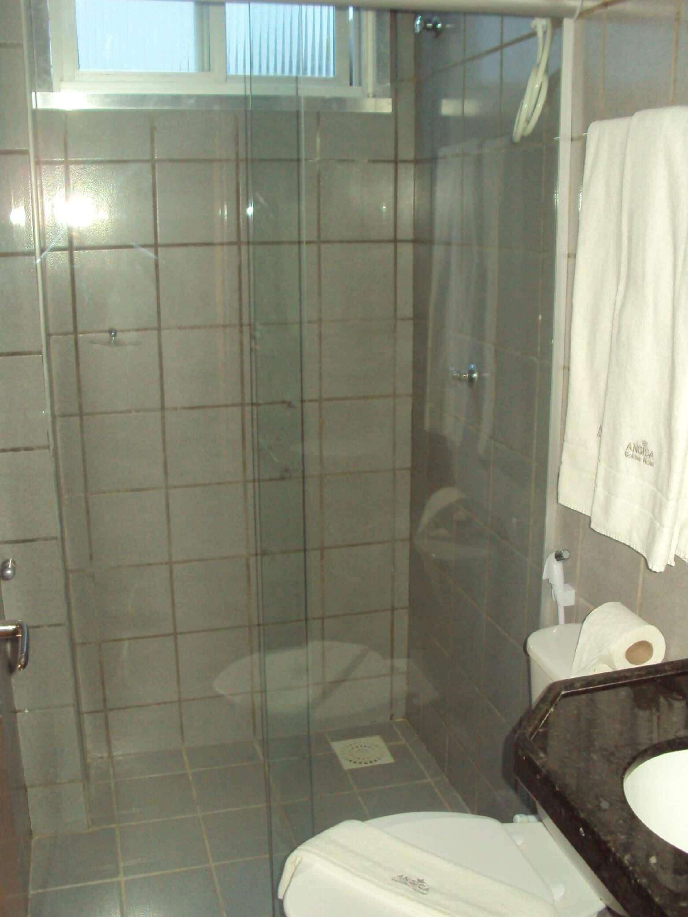 Une salle de bain dotée d’une douche à parois de verre, de toilettes et d’un lavabo avec un plan de travail foncé.