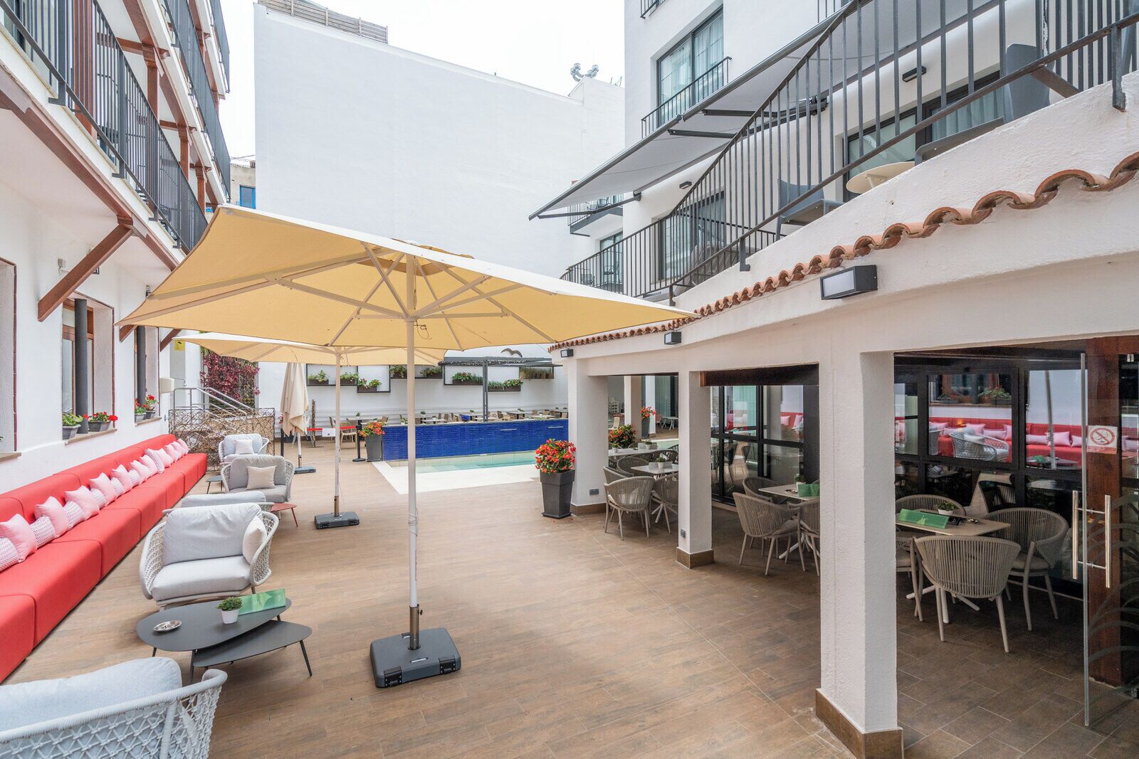 Une terrasse extérieure dotée d’une piscine, de coins salon et d’un espace repas couvert.