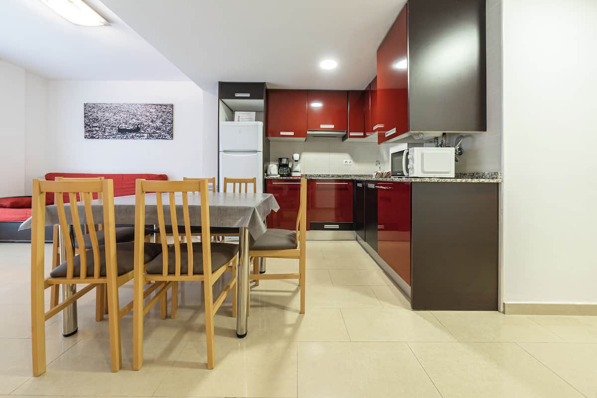 Uma cozinha compacta com armários vermelhos, micro-ondas e máquina de café.