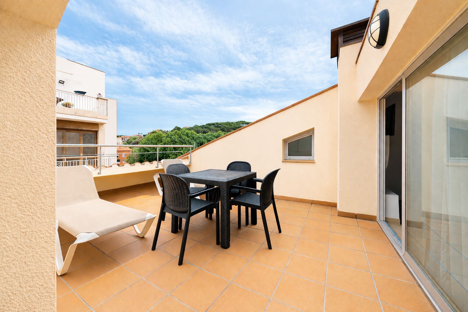 A balcony with a table and chairs, a sofa, and a view of the cityscape.