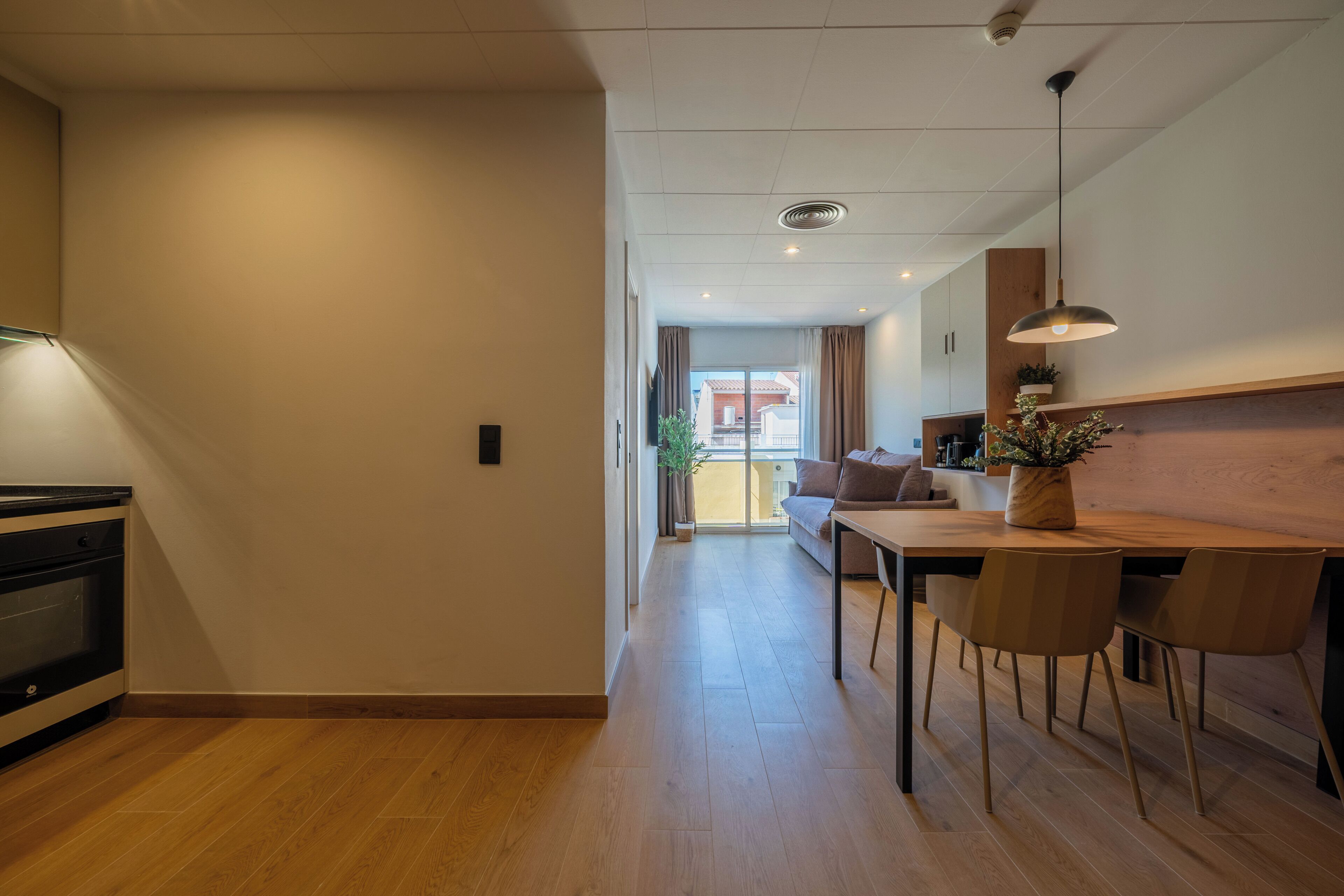 Una cocina moderna con comedor, suelo de madera y vistas al exterior.