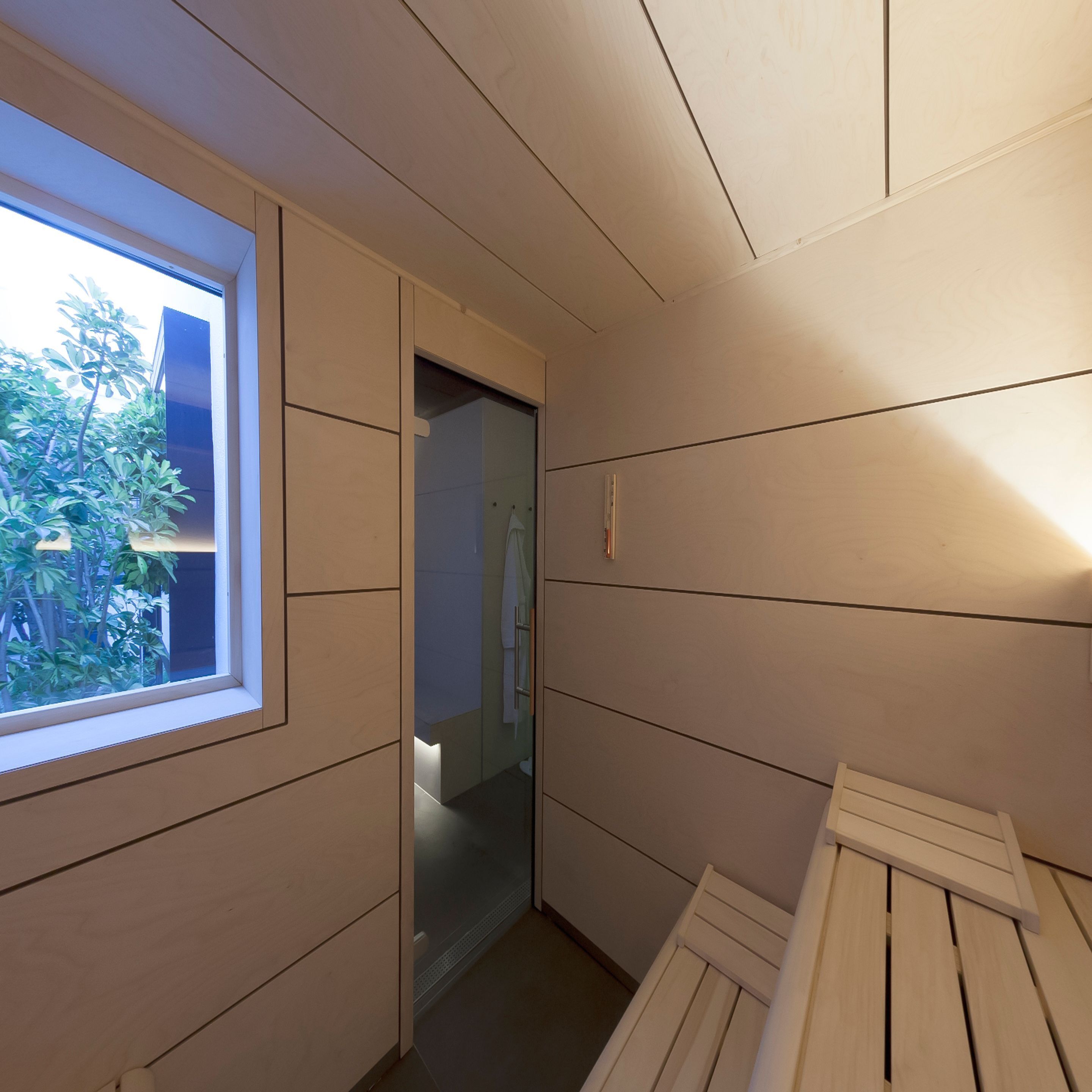 A narrow hallway with wooden paneling, a window, and a door leading to another room.