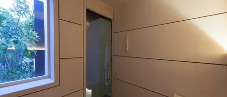 A narrow hallway with wooden paneling, a window, and a door leading to another room.