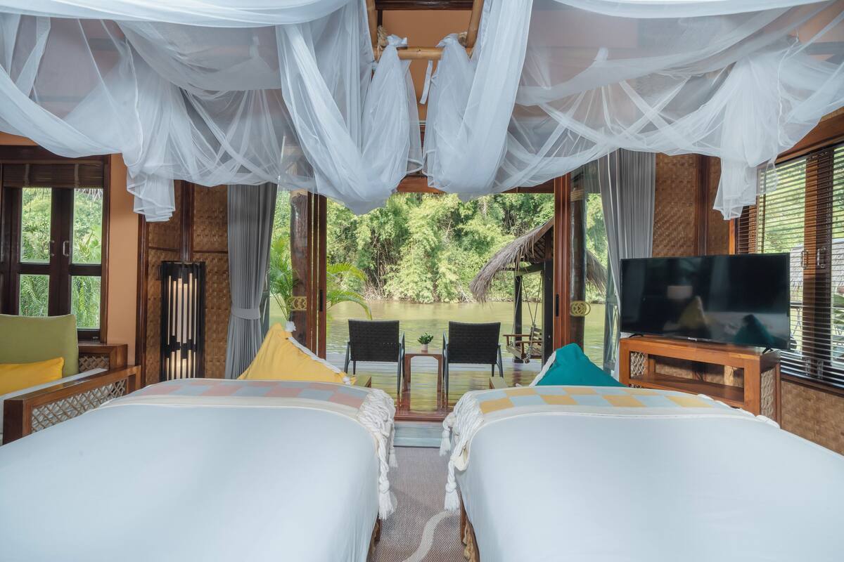 Une chambre avec deux lits, une télévision et une vue sur la verdure.