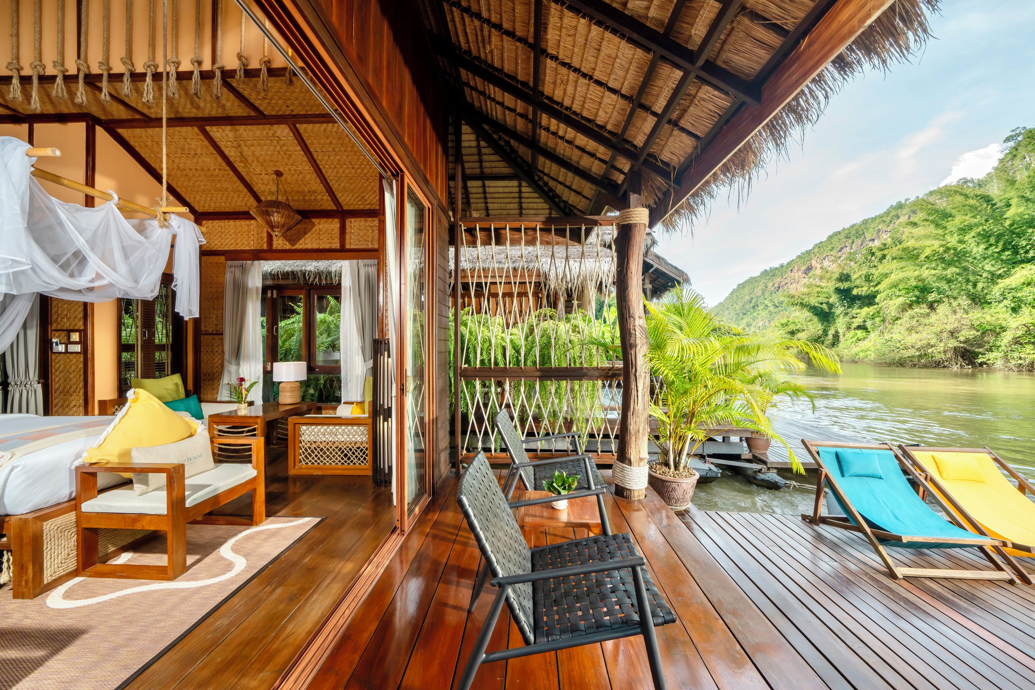A wooden deck with a bed, chairs, and a table.