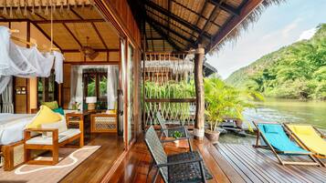 A wooden deck with a bed, chairs, and a table.