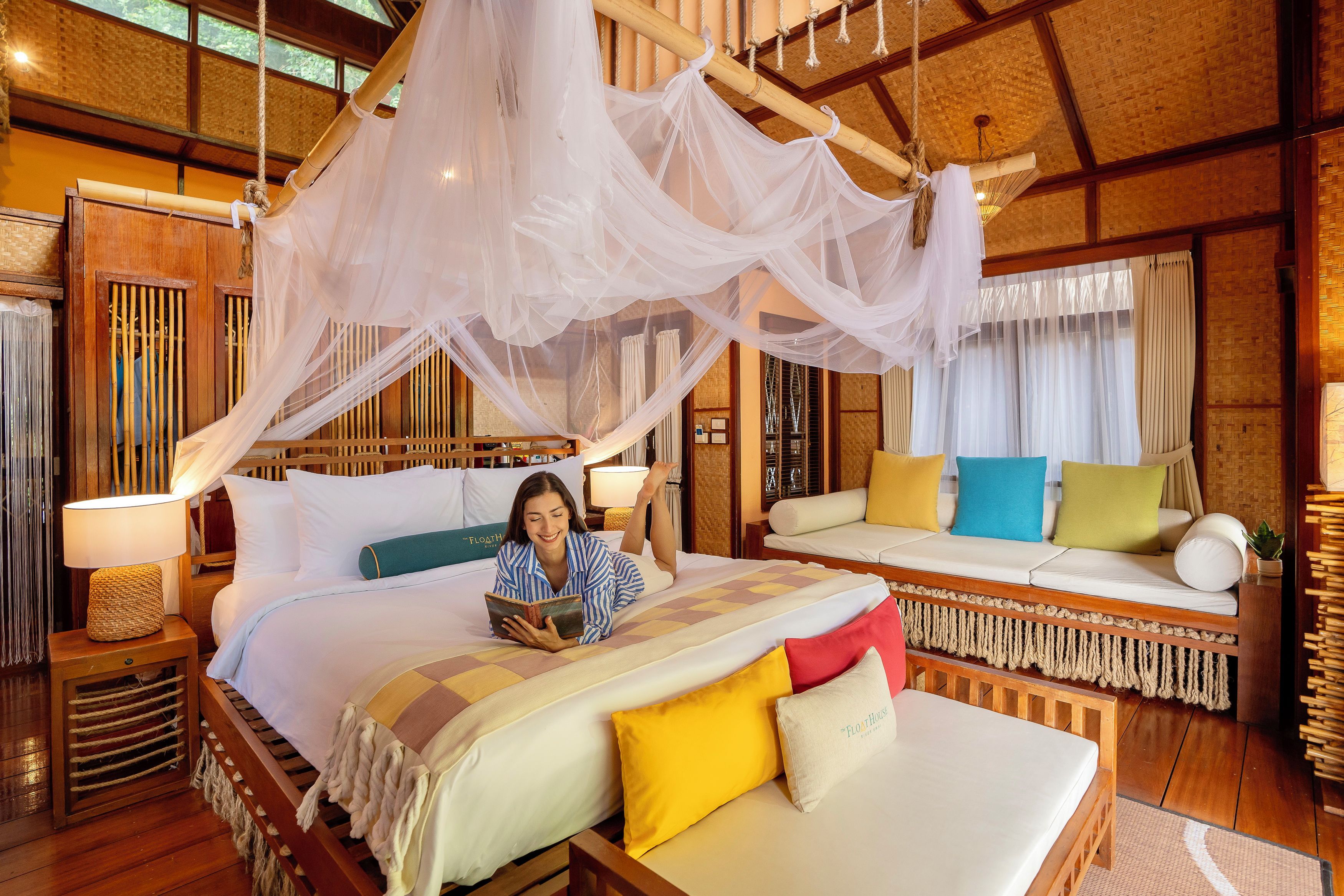 A room with a bed, a sofa, and a reading area with a person.