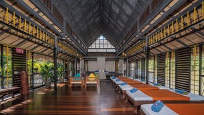 Un área de spa con suelos de madera, varias camillas de masaje y un techo alto con tragaluces.