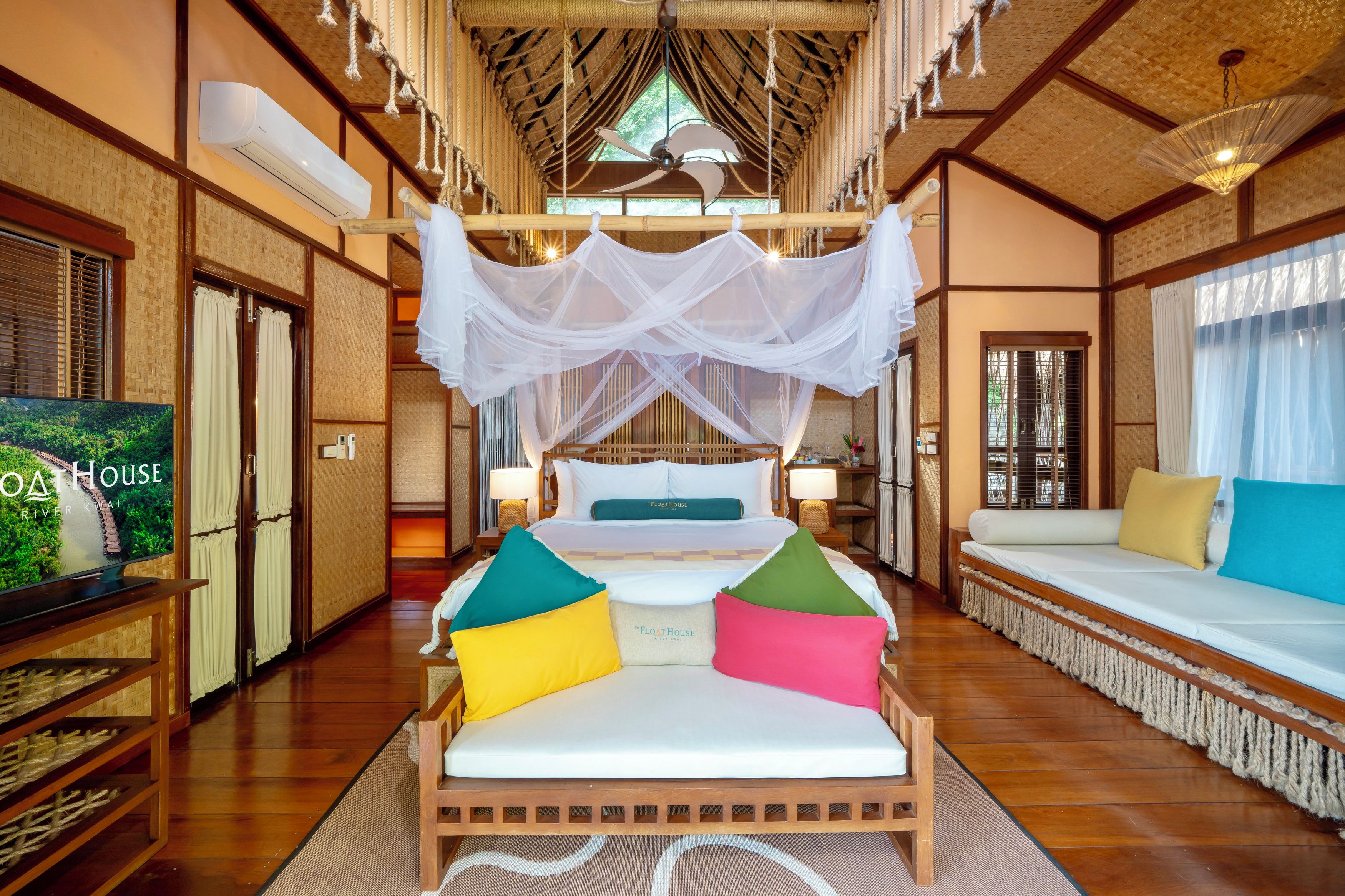 A hotel room with a bed, a sofa, a TV, and a canopy bed.