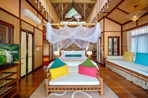 Una habitación de hotel con una cama, un sofá, un televisor y una cama con dosel.