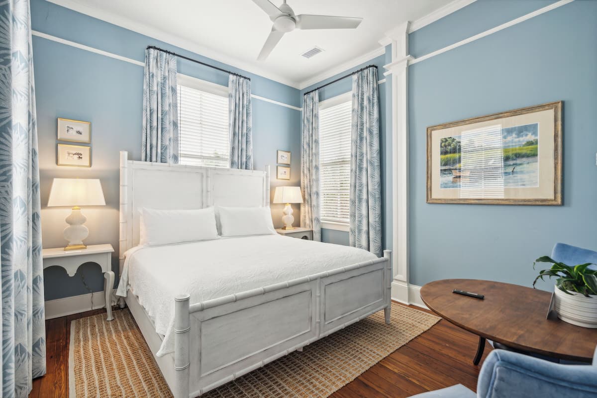 A bedroom with a bed, bedside tables, a round table, and a chair.