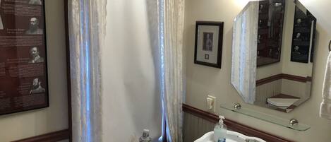 A bathroom with a white sink, a mirror, a framed picture, and a poster on the wall.